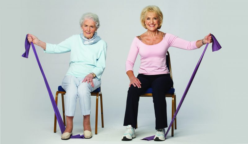 Rosemary Conley and her elderly Mother in Law seated, demonstrating an exercise with a toning band