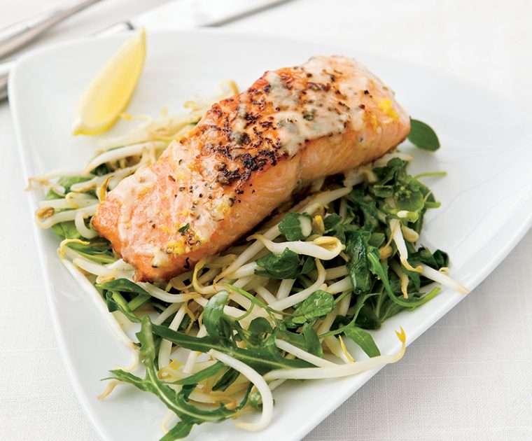 A piece of baked salmon on a bed of stir fried beansprouts and green vegetables