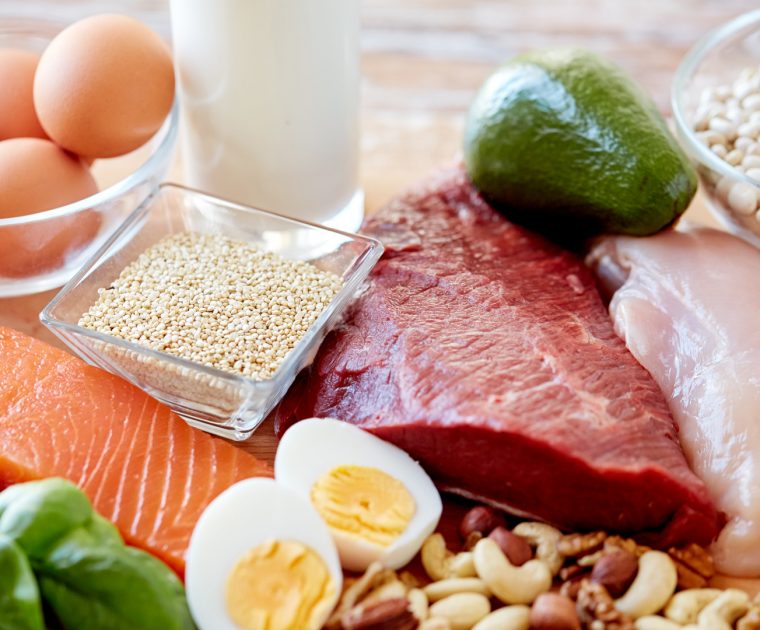 Close up of different foodstuffs required to eat well on table including eggs, milk, meat potatoes, pulses and beans