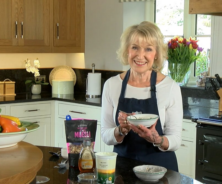 Rosemary Conley smiling in her kitchen holding a bowl of Austrian Muesli