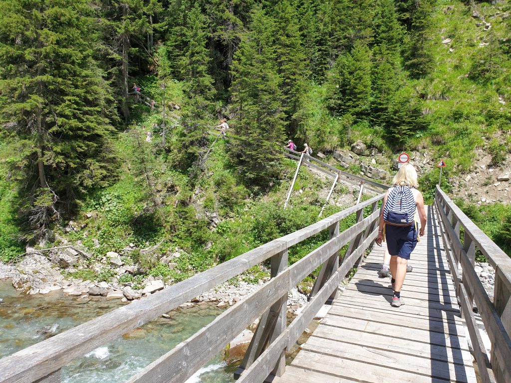 Austrian Activity Holiday group walking across the river on a narrow wooden foot-bridge