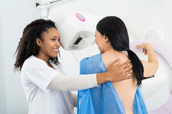 A happy female doctor assisting a woman undergoing a breast screening Mammogram X-ray Test