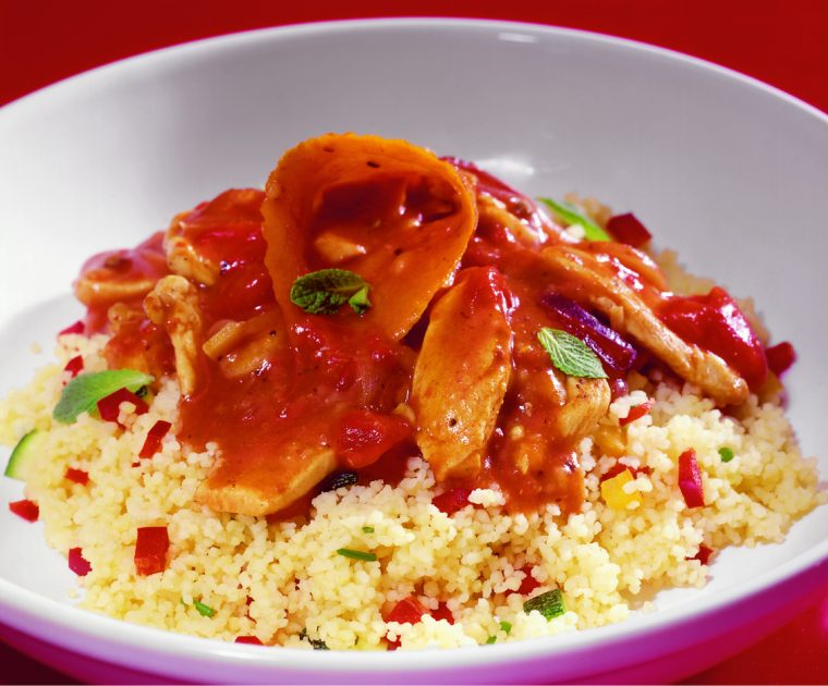 Tunisian Chicken in a rich, spicy orange sauce served on a bed of couscous