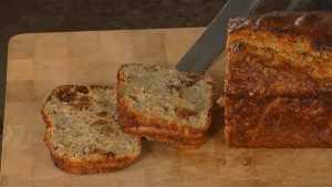 Banana and Sultana loaf cake on a cutting board with a couple of pieces sliced revealing the moist banana sponge and juicy sultanas.