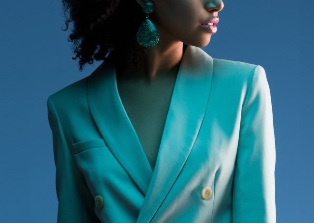 Image of a stylish woman wearing a low cut white jacket on a plain blue background