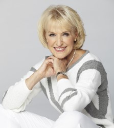 Rosemary Conley sitting cross legged on the floor wearing a white and grey jumper with her elbos on her knees and her hands clasped under her chin