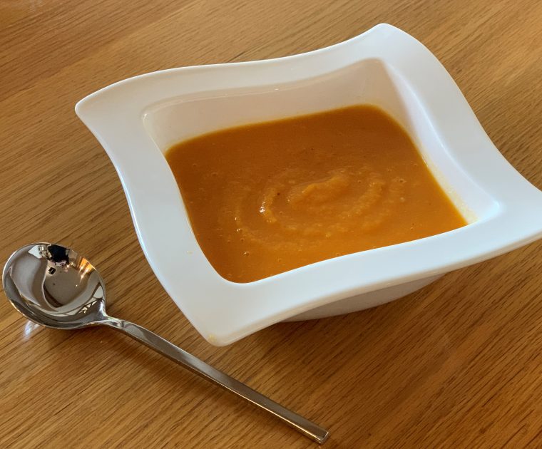 Sweet Potato and Ginger Soup in a square shaped bowl with a spoon