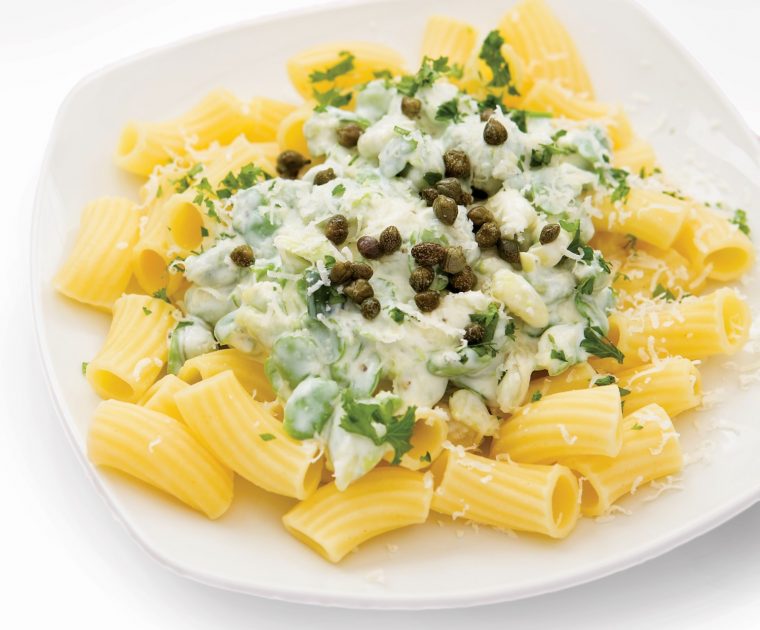 A dish of rigatoni pasta topped with a mixture of crushed broad beans, greek yogurt, capers, mint, chives and parsley