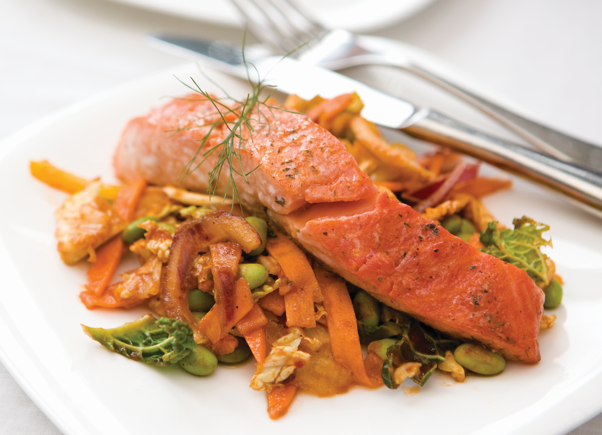 Tandoori Salmon with Spicy Noodles is a fillet of salmon dusted with curry powder and baked, resting on a bed of stir-fired noodle and vegetables