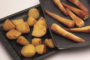Two baking trays contining golden crisp and golden dry roasted potatoes and parsnips