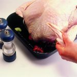 Sit the turkey on top. Pull out the wing tips and twist, tucking them under the bird; this will prevent them from burning during cooking.
