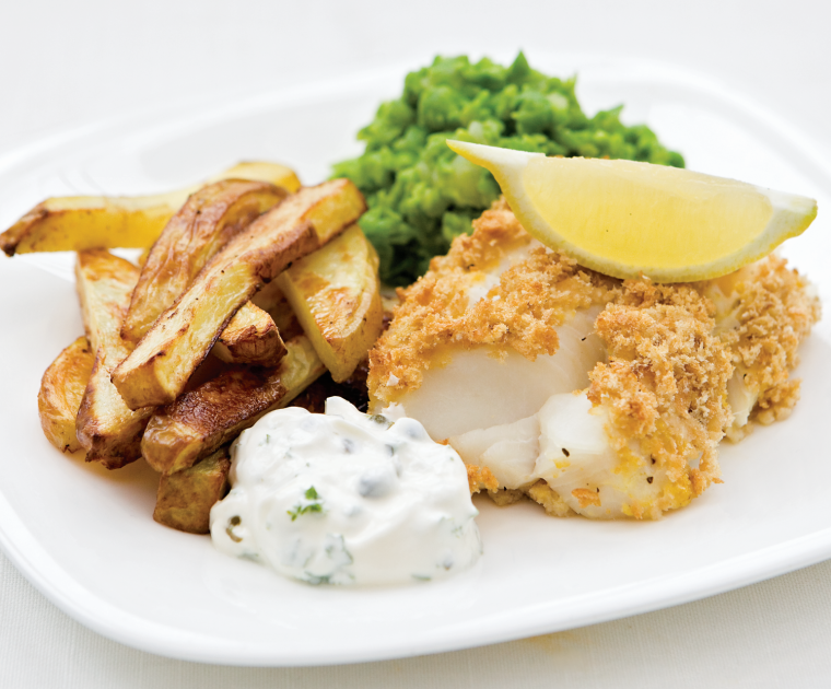 A fillet of cod in homemade breadcrumbs with a lemon wedge on top, served with home-made chips, lightly mushed garden peas and a blob of home-made tartare sauce.