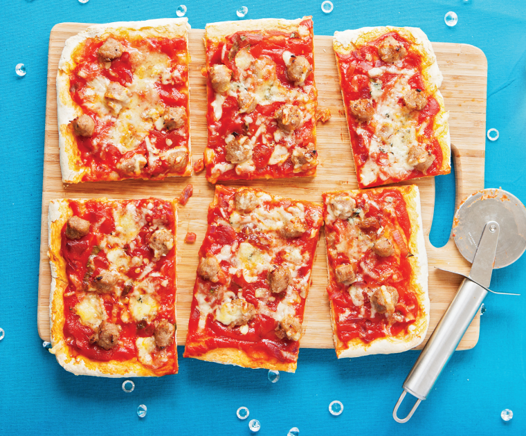 Christmas Pizza made with a tomato topped base, small meatballs of sausage meat and chutney, and sprinkled with two cheeses.