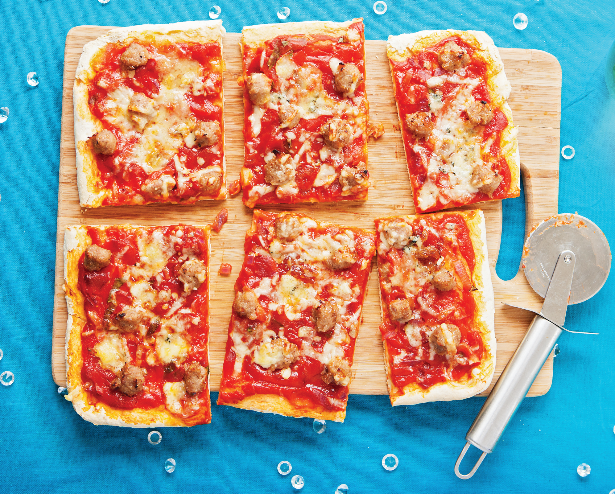 Christmas Pizza made with a tomato topped base, small meatballs of sausage meat and chutney, and sprinkled with two cheeses.