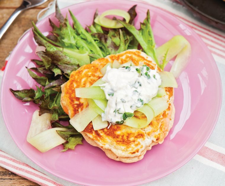 Smoked Salmon drop scones on a pink plate topped with a creamy suace and served with a side salad of green leaves as a light lunch