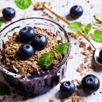 Blueberry crumble is made in an individual ramekin dish with blueberries with sugar and cinemon topped with a crumble of oats and almonds and baked.