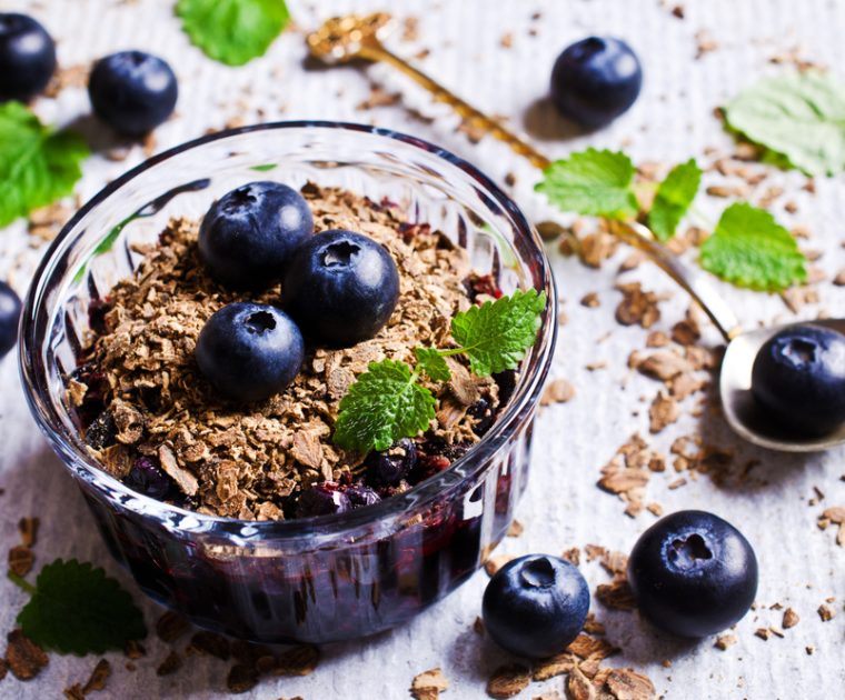 Blueberry crumble is made in an individual ramekin dish with blueberries with sugar and cinemon topped with a crumble of oats and almonds and baked.