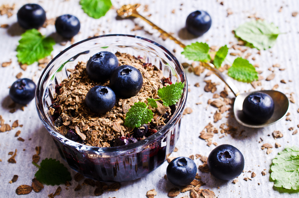 Blueberry crumble is made in an individual ramekin dish with blueberries with sugar and cinemon topped with a crumble of oats and almonds and baked.