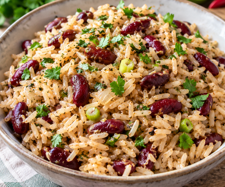 Caribbean Style Rice and Peas is a bowl of long-grain white rice with red kidney beans, chopped spring onion and other herbs and spices.