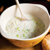 Bread Sauce with Leeks is a whire creamy sauce thickened with bread crumbs and finely chopped leeks shown here being mixed in a mixing bowl with a wooden spoon.