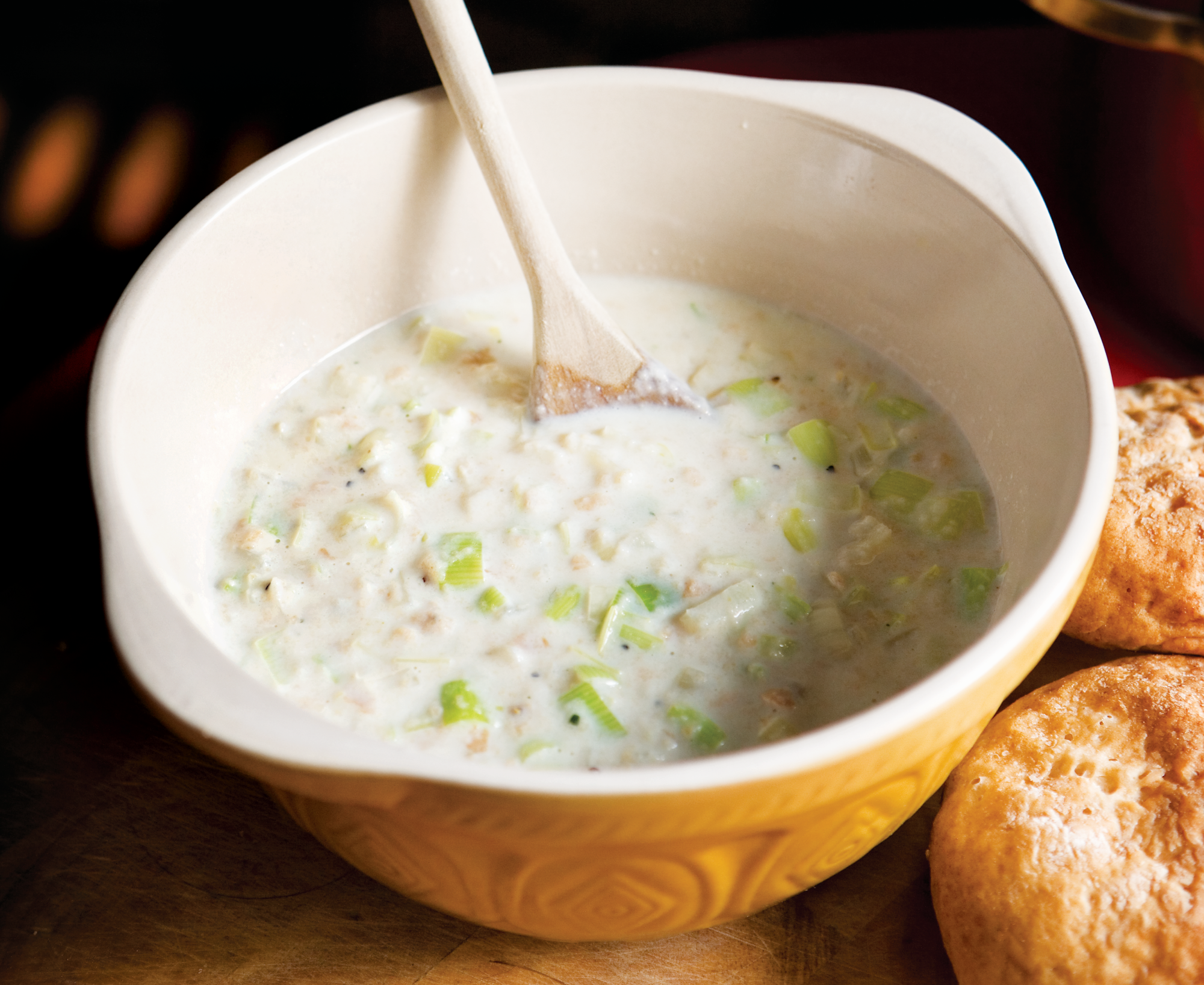 Bread Sauce with Leeks is a whire creamy sauce thickened with bread crumbs and finely chopped leeks shown here being mixed in a mixing bowl with a wooden spoon.