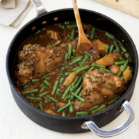 Braised Lamb Shanks in a pan with gravy and green beans