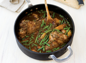 Braised Lamb Shanks in a pan with gravy and green beans