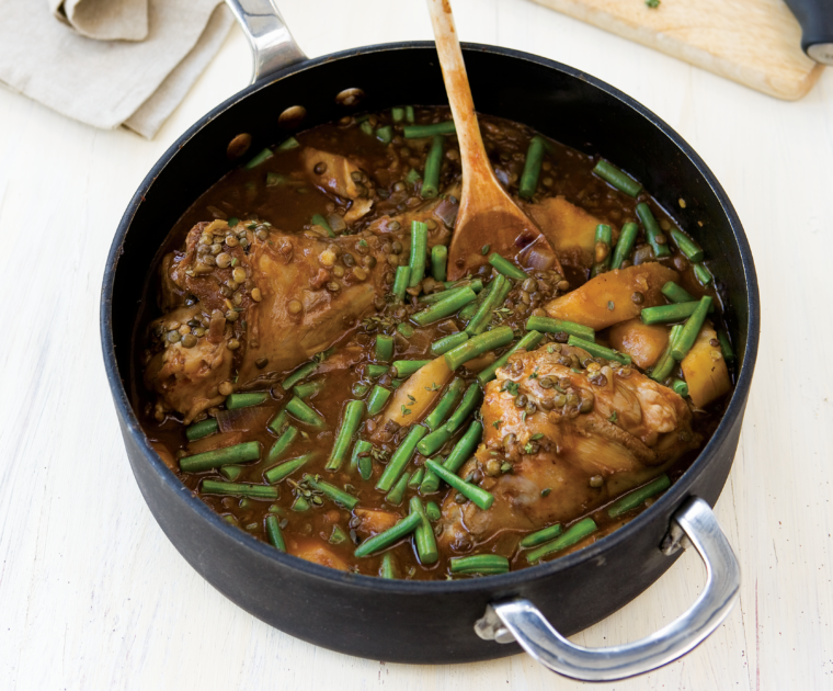 Braised Lamb Shanks in a pan with gravy and green beans
