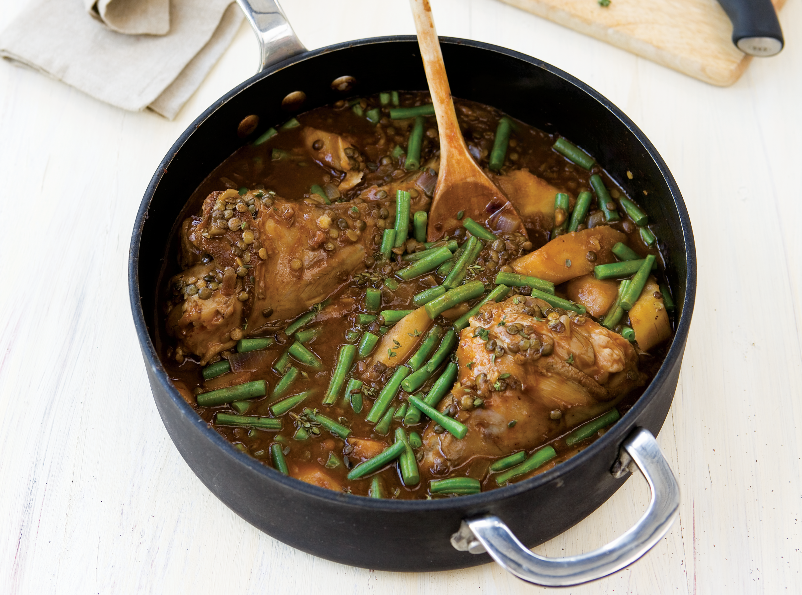 Braised Lamb Shanks in a pan with gravy and green beans