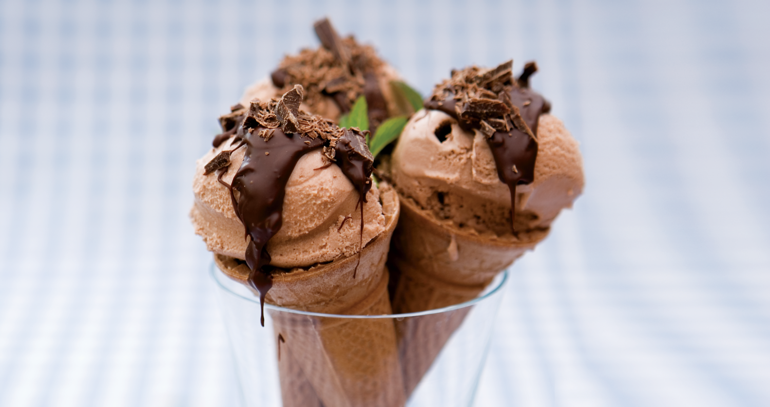 Low-fat home-made chocolate mint ice cream, made from greek yogurt, custard and cocoa powder, in a wafer cone topped with melted chocolate and decorated with a mint leaf.
