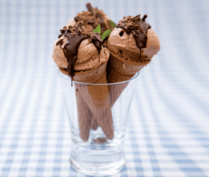 low-fat home-made chocolate mint ice cream, made from greek yogurt, custard and cocoa powder, in a wafer cone topped with melted chocolate and decorated with a mint leaf.