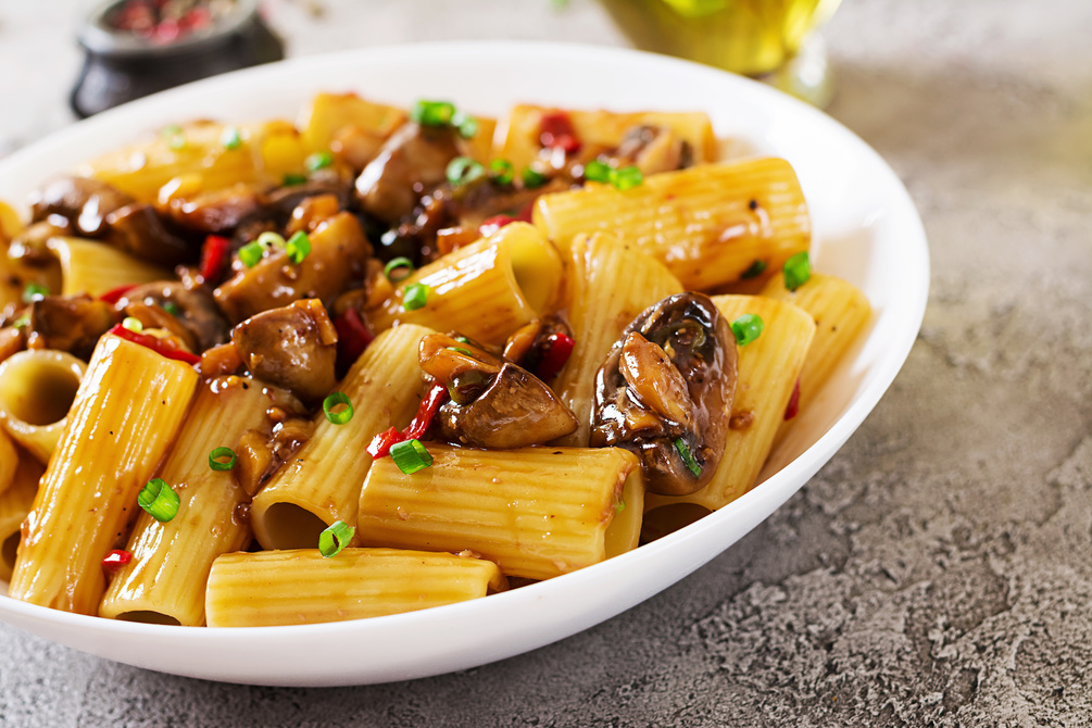 A bowl of Rigatoni Pasta Miso and Chilli Mushrooms. Rigatoni pasta tubes in a glistening sauce made from miso paste, white wine and sesame oil with chestnut mushrooms sprinkled with chilli and fennel seeds.